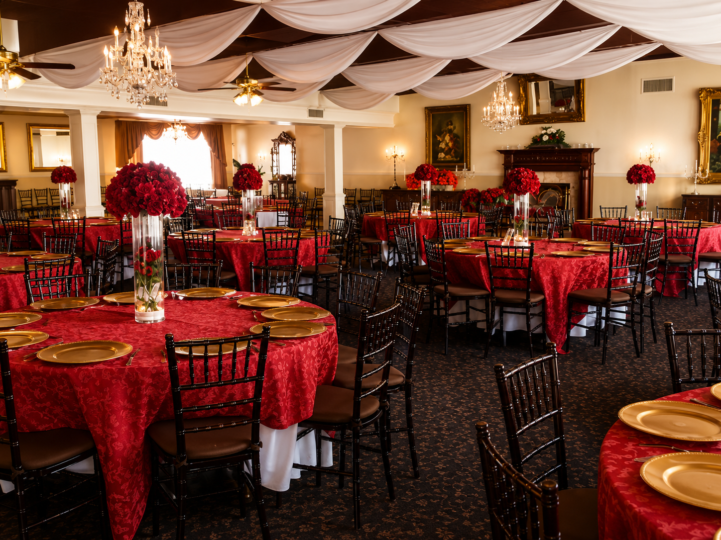 Elegant ballroom reception with red tablecloths, gold chargers and crystal chandeliers