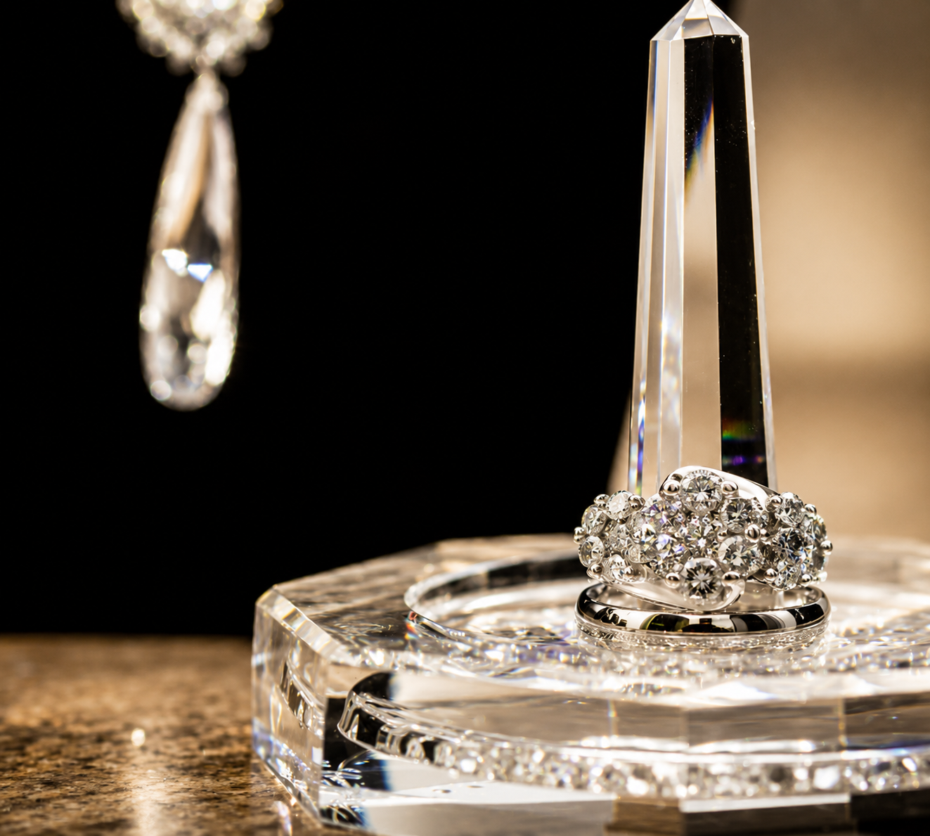 Diamond wedding rings displayed on a crystal obelisk with chandelier detail
