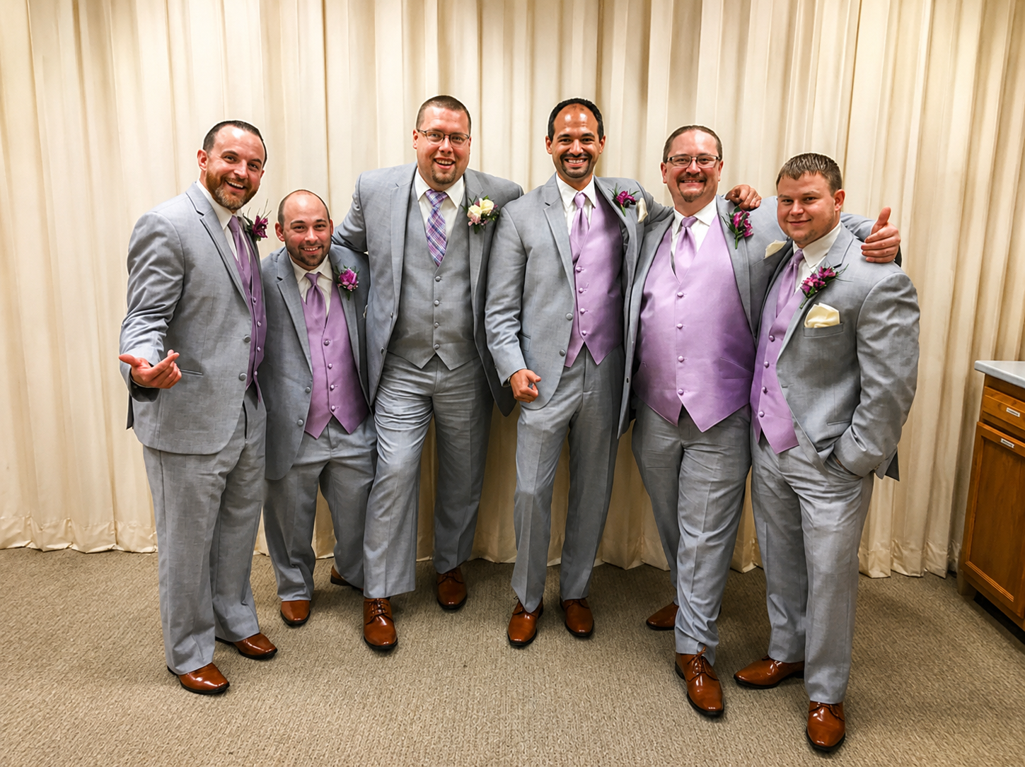 Groom and groomsmen in grey suits with lavender vests and boutonnieres